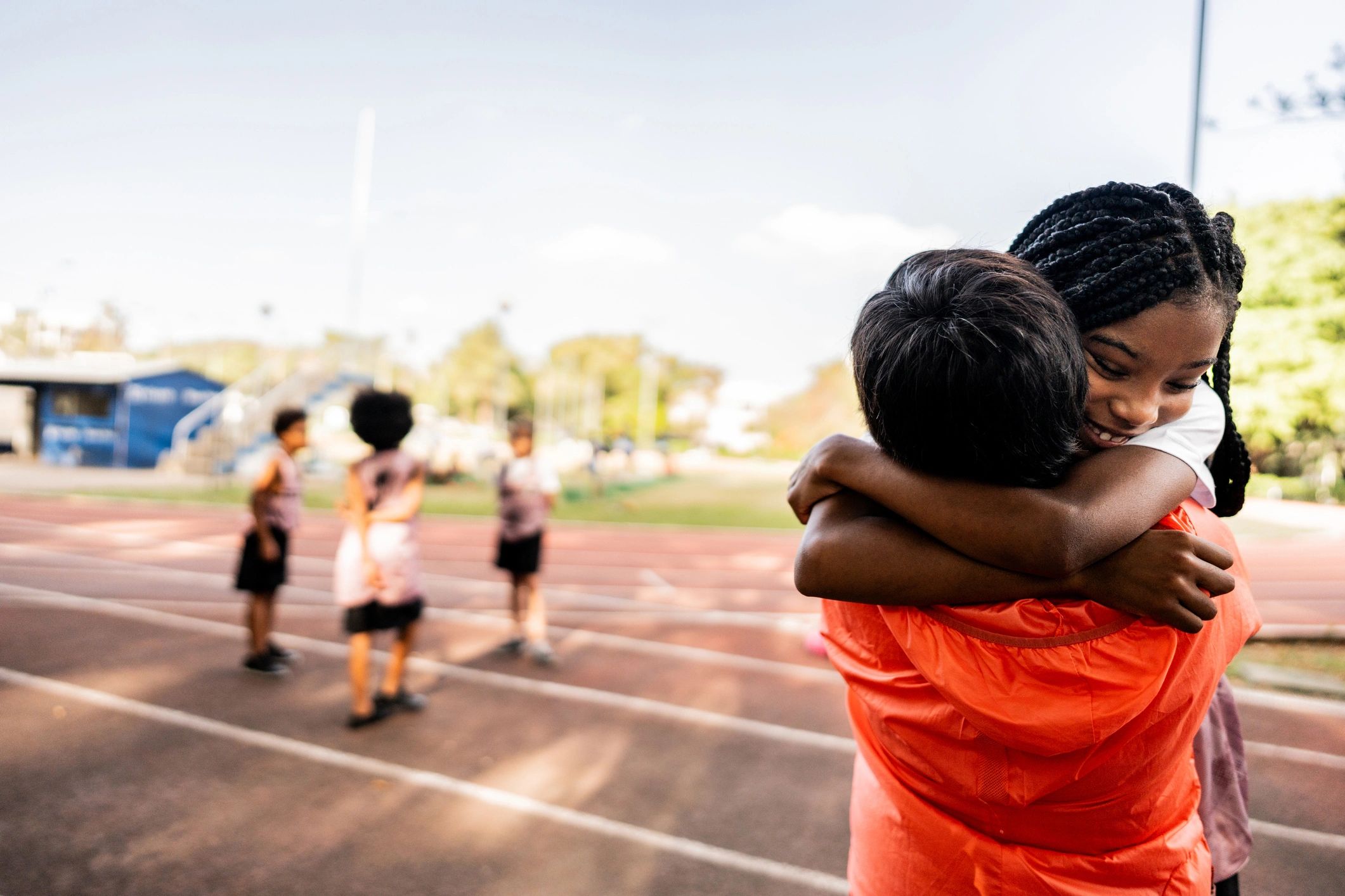 Youth athlete embracing a supportive adult